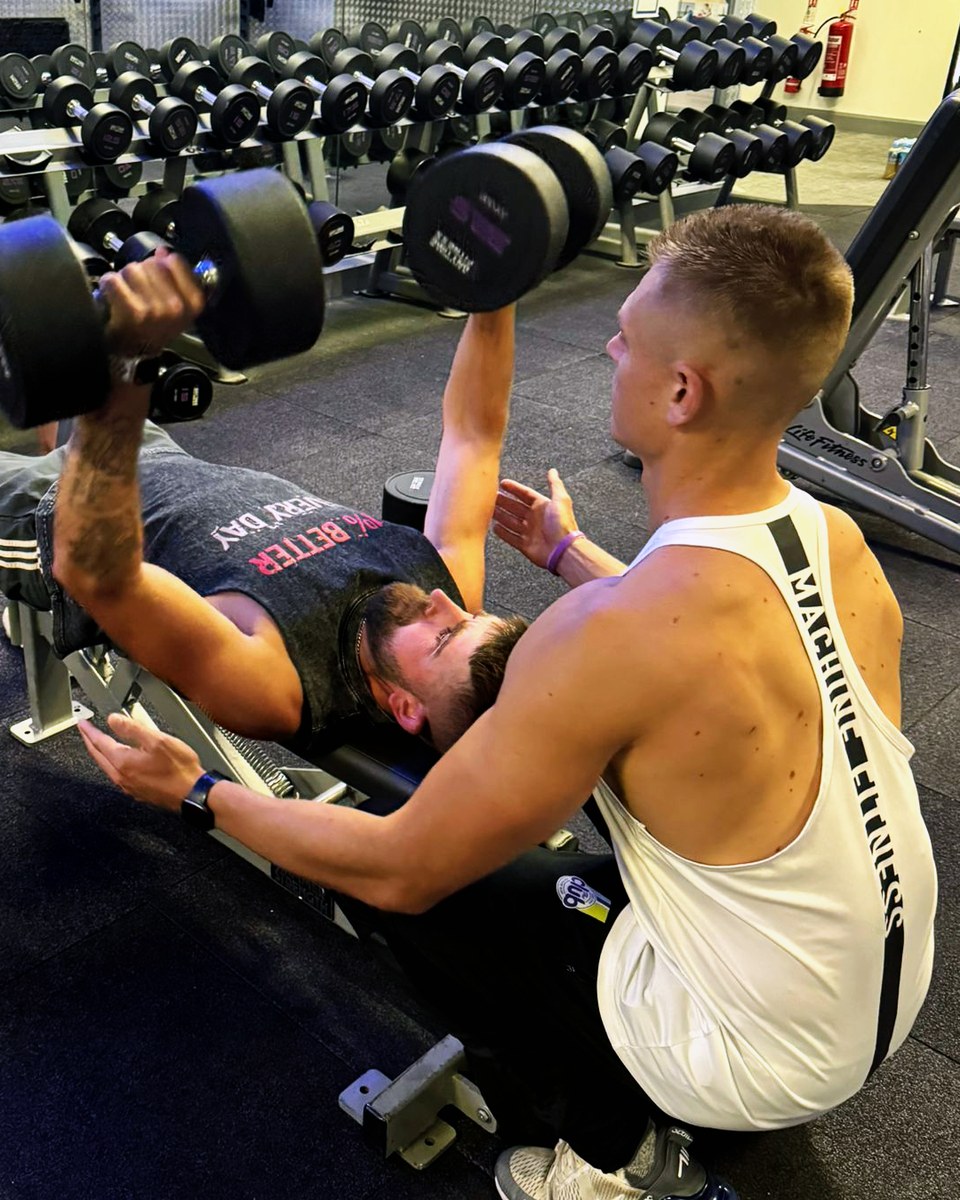 Personal trainer correcting lifting technique